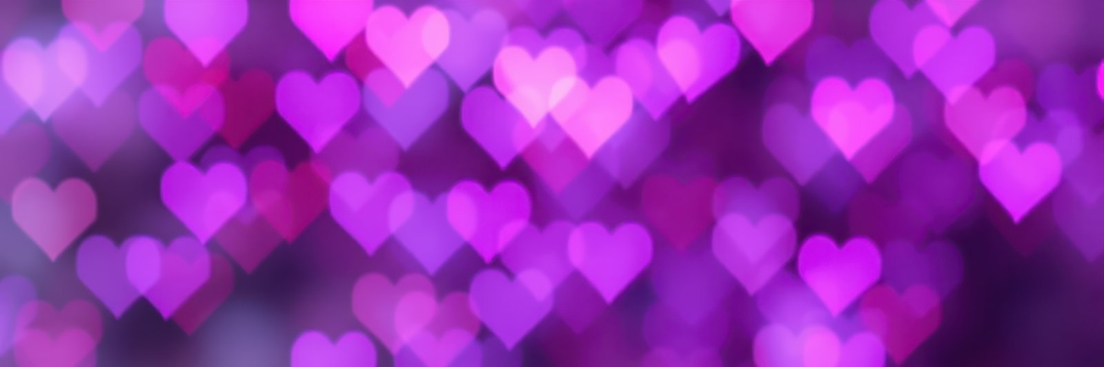 Colorful heart-shaped bokeh lights create a romantic and festive atmosphere in a purple hue during a celebration or event